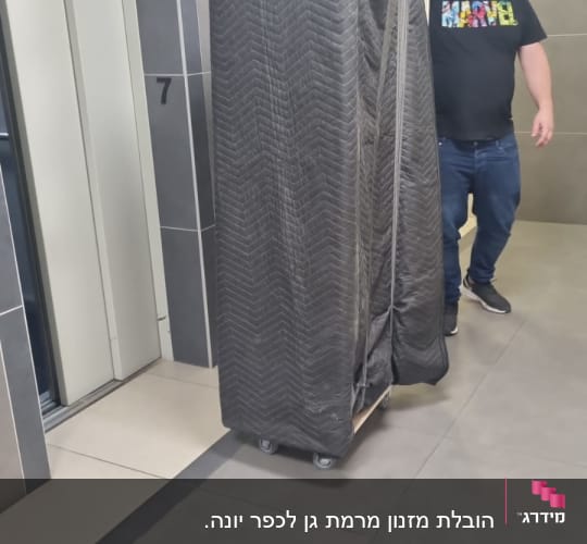 אדם מזיז רהיט עטוף על עגלה במסדרון